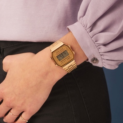 Relógio digital dourado com pulseira metálica no pulso