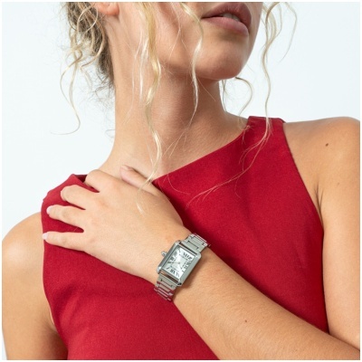 Relógio de pulso prateado com mostrador branco e números romanos no pulso de mulher com blusa vermelha