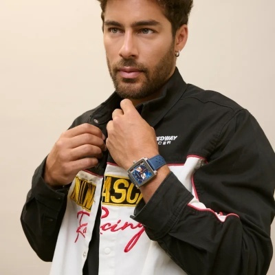 Homem com relógio azul quadrado e roupa preta e branca com texto NASCRU Racing