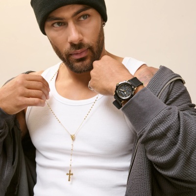 Homem a usar relógio preto com detalhes dourados e cadeia dourada com cruz