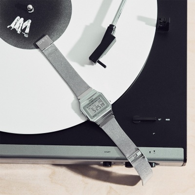 Relógio digital prateado sobre gira-discos com vinil branco