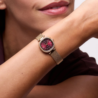 Relógio de pulso dourado com mostrador vermelho e cristais no pulso feminino
