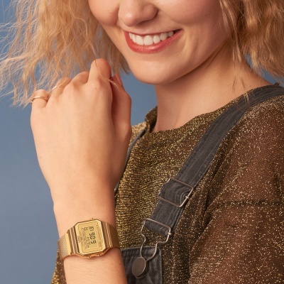 Relógio digital Casio dourado com bracelete metálica de malha fina no pulso de uma mulher