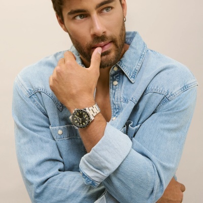 Homem com camisa jeans azul e relógio de pulso de aço