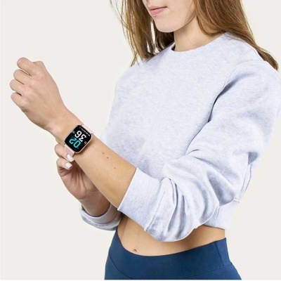 Relógio inteligente no pulso de mulher com camisola cinzenta clara e calças azuis.