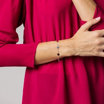 Pulseira fina com pequenas flores decorativas em braço com vestido rosa