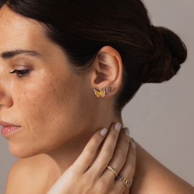 Brincos de borboleta dourados e castanhos em orelha feminina com cabelo preso