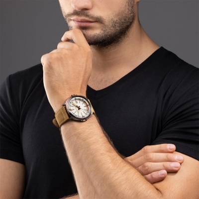 Relógio de pulso masculino com bracelete castanha e mostrador branco usado por homem de t-shirt preta