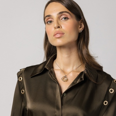 Mulher com camisa verde-oliva e colar prateado com pendente