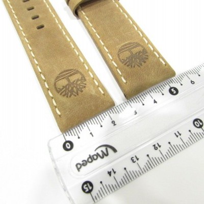 Duas correias de relógio em couro castanho claro com costuras brancas ao lado de uma régua transparente.