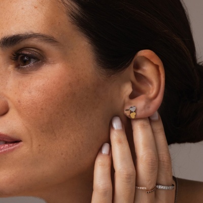 Brinco de três corações em prata, dourado e bronze numa orelha feminina