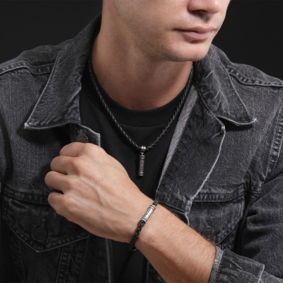 Homem com colar e pulseira pretos com detalhes metálicos