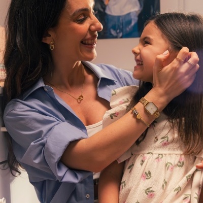 Mulher com camisa azul e menina com vestido branco com padrão floral sorrindo