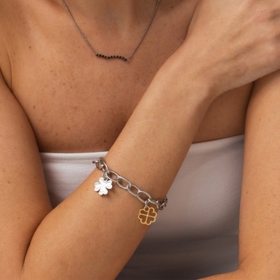 Pulseira prateada com pendentes em forma de trevo no pulso de mulher