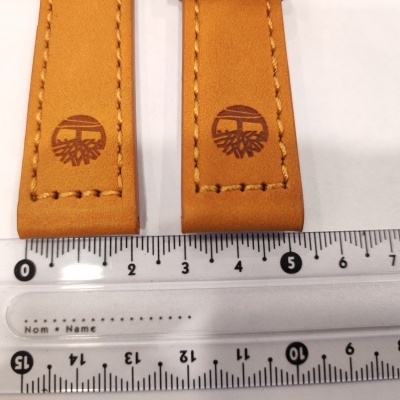 Duas correias de couro castanho com logotipo de árvore ao lado de régua transparente