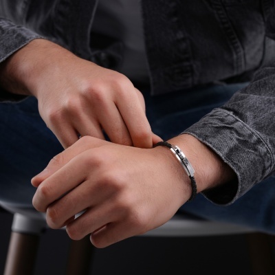 Pulseira preta com placa metálica prateada gravada com 