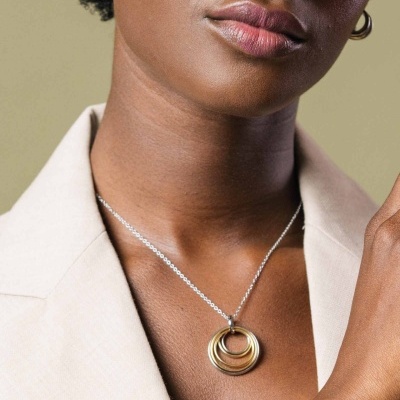 Colar com pendentes circulares dourado e prateado em mulher com blazer bege