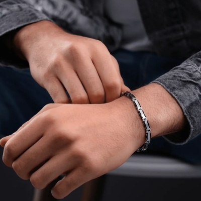 Pulseira masculina de metal prateado com elos retangulares no pulso de homem