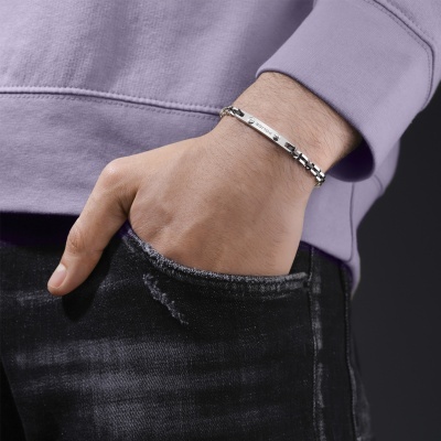 Pulseira metálica prateada com placa POLICE no pulso de uma pessoa