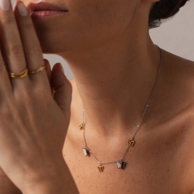 Colar com borboletas prateadas e douradas no pescoço de uma mulher