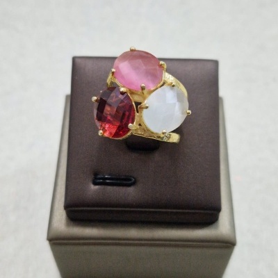 Anel dourado com três pedras coloridas exposto em base de couro