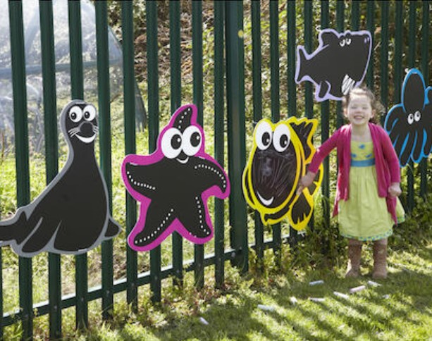 Conjunto de Quadros - Mark Making Chalkboard Reef Painéis decorativos de animais marinhos coloridos numa grade ao ar livre com uma criança ao lado