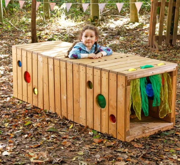 Mini Toddler Interactive Tunnel - Túnel Interativo Estrutura de madeira com janelas redondas coloridas e cortinas verdes com criança apoiada