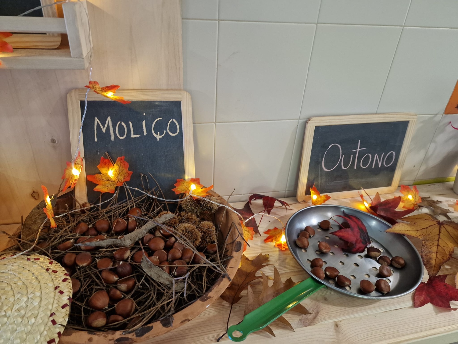 Mostra de frutos de outono com castanhas, folhas artificiais e placas de madeira com texto
