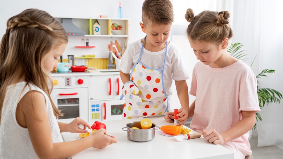 Crianças brincando com brinquedos de cozinha em ambiente infantil