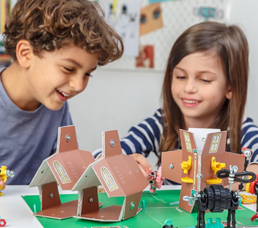FarmBit — Semeia, cresce e pastoreia! Crianças a brincar com casas e peças de construção de cartão e plástico colorido