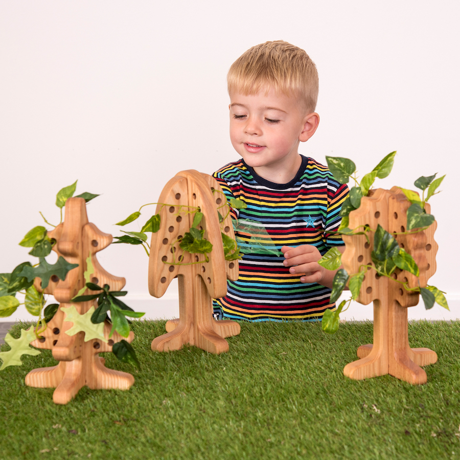 Set Árvores de Enfiamento TTS Criança a brincar com árvores decorativas de madeira e folhas verdes numa superfície de relva artificial