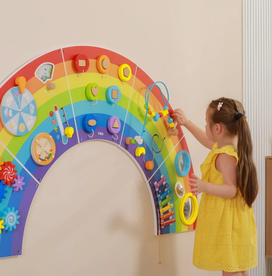 Painel de Atividades Arco-Íris Painel de atividades infantil colorido em forma de arco-íris na parede com criança brincando