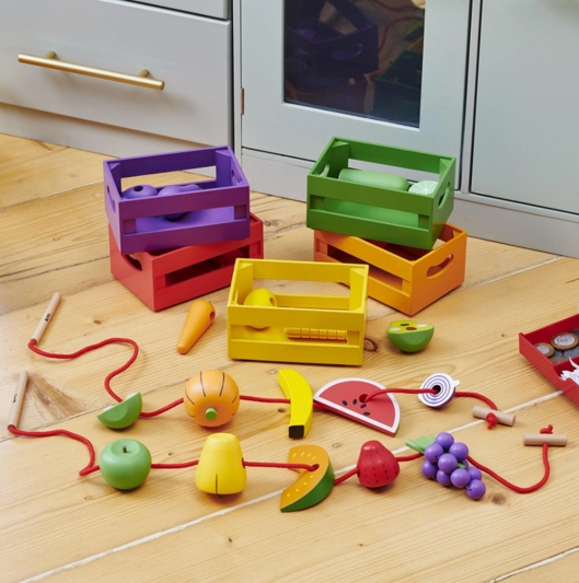 Caixas de Classificação de Frutas e Legumes em Madeira Brinquedos de madeira coloridos de frutas e legumes com caixas coloridas sobre chão de madeira clara