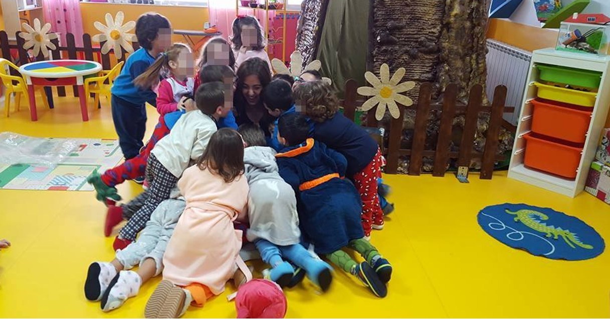 Tapete azul com cavalo-marinho verde numa sala infantil com crianças e estante colorida