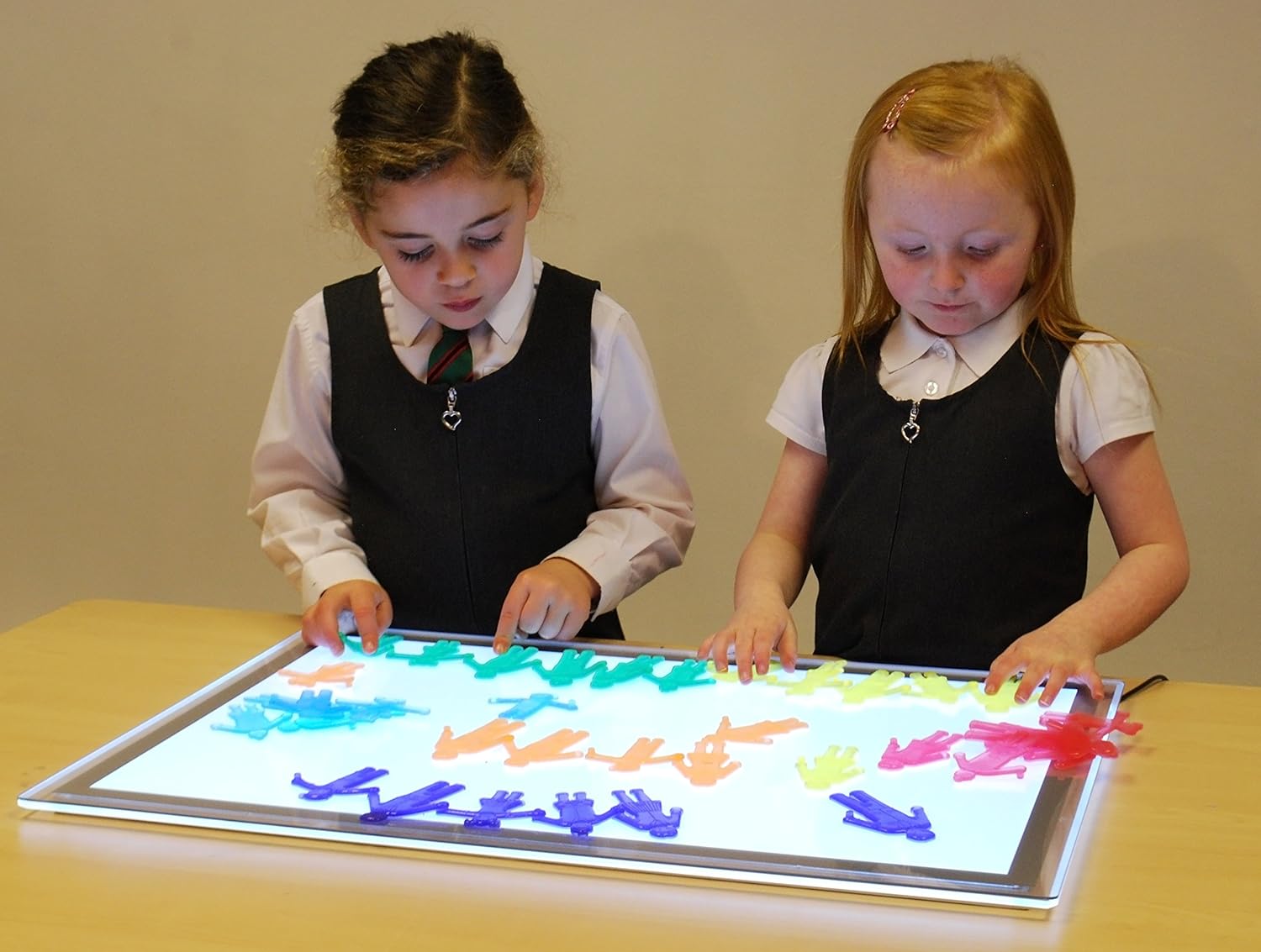 SiliShapes - Ligação de Pessoas Duas meninas a brincar com figuras coloridas num painel de luz