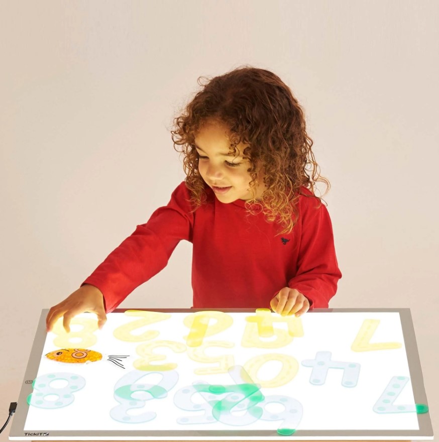 Criança a usar mesa luminosa com números coloridos