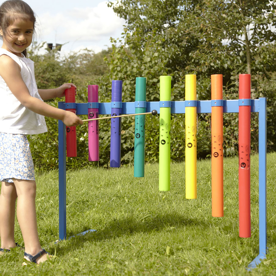 Estrutura Musical Boomwhacker para Exterior Criança a tocar xilofone de tubos coloridos em suporte azul no exterior, em relvado.