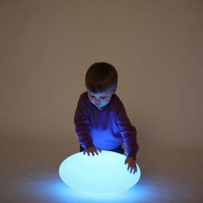 Criança com objeto oval luminoso azul em fundo bege