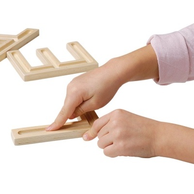Mãos infantis montando quebra-cabeça de letras de madeira clara