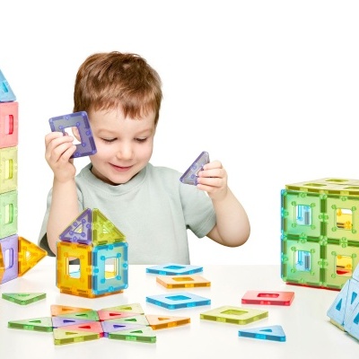 Criança a brincar com blocos magnéticos coloridos de plástico translúcido.