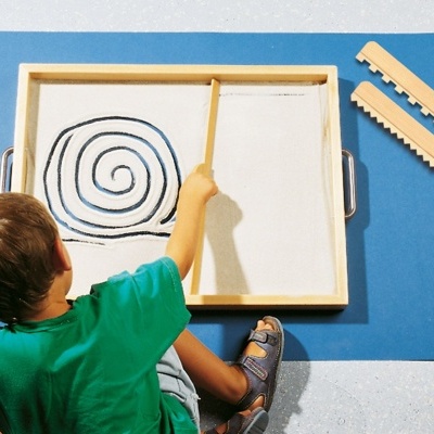 Criança desenhando espiral numa moldura de madeira sobre tapete azul