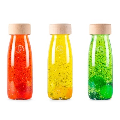Três garrafas de vidro coloridas com tampa de madeira em fundo branco