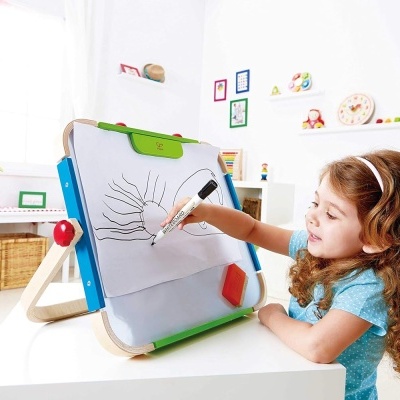 Menina a desenhar num quadro branco de dupla face com moldura colorida e suporte de madeira