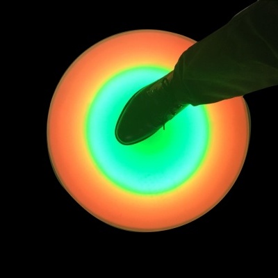 Bota verde sobre disco luminoso colorido