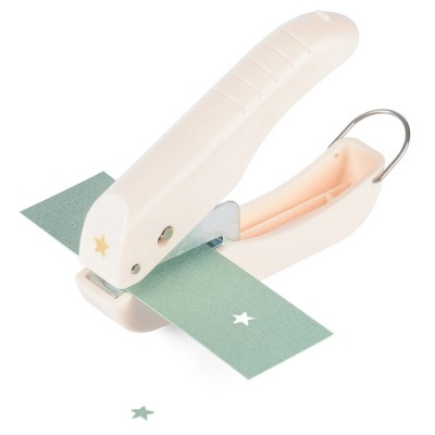 Cortador de papel bege com detalhe de estrela dourada cortando papel verde com estrela branca