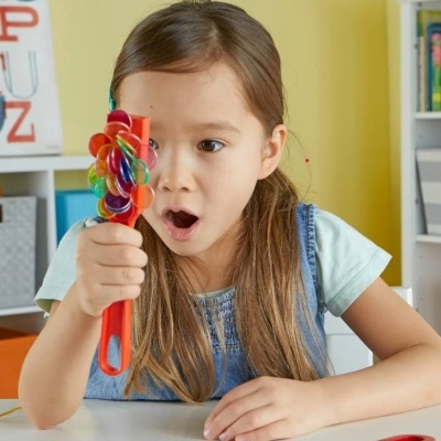 Menina a segurar brinquedo colorido com fundo de estante e decoração interna