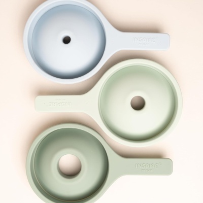 Três moldes de silicone redondos com cabo em azul e verdes, com buraco central e texto em relevo nos cabos.