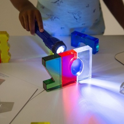 Bloquinhos coloridos de acrílico e lanterna sobre mesa branca