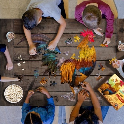 Crianças montando puzzle colorido de galo numa mesa com tigelas de pipocas