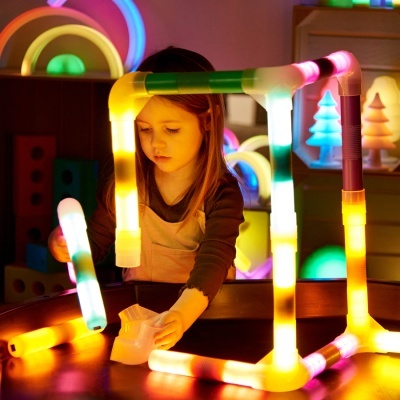 Estrutura cúbica de tubos plásticos iluminados coloridos com criança a brincar